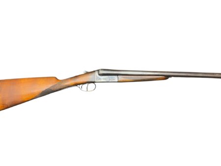 Side view of a vintage break-action shotgun with a wooden stock and long metal barrel, laid horizontally