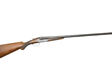 Double-barreled shotgun with wooden stock laid diagonally across a white background.