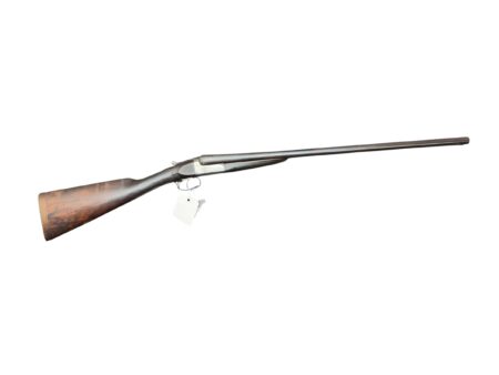 Side view of a vintage shotgun with a wooden stock and long metal barrel