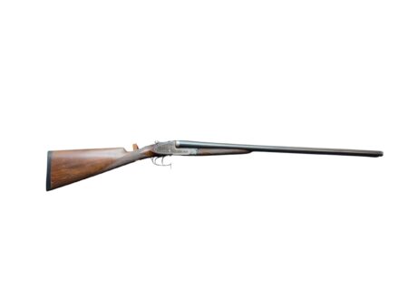 Shotgun with a wooden stock and double barrels lying across a white background, side view.