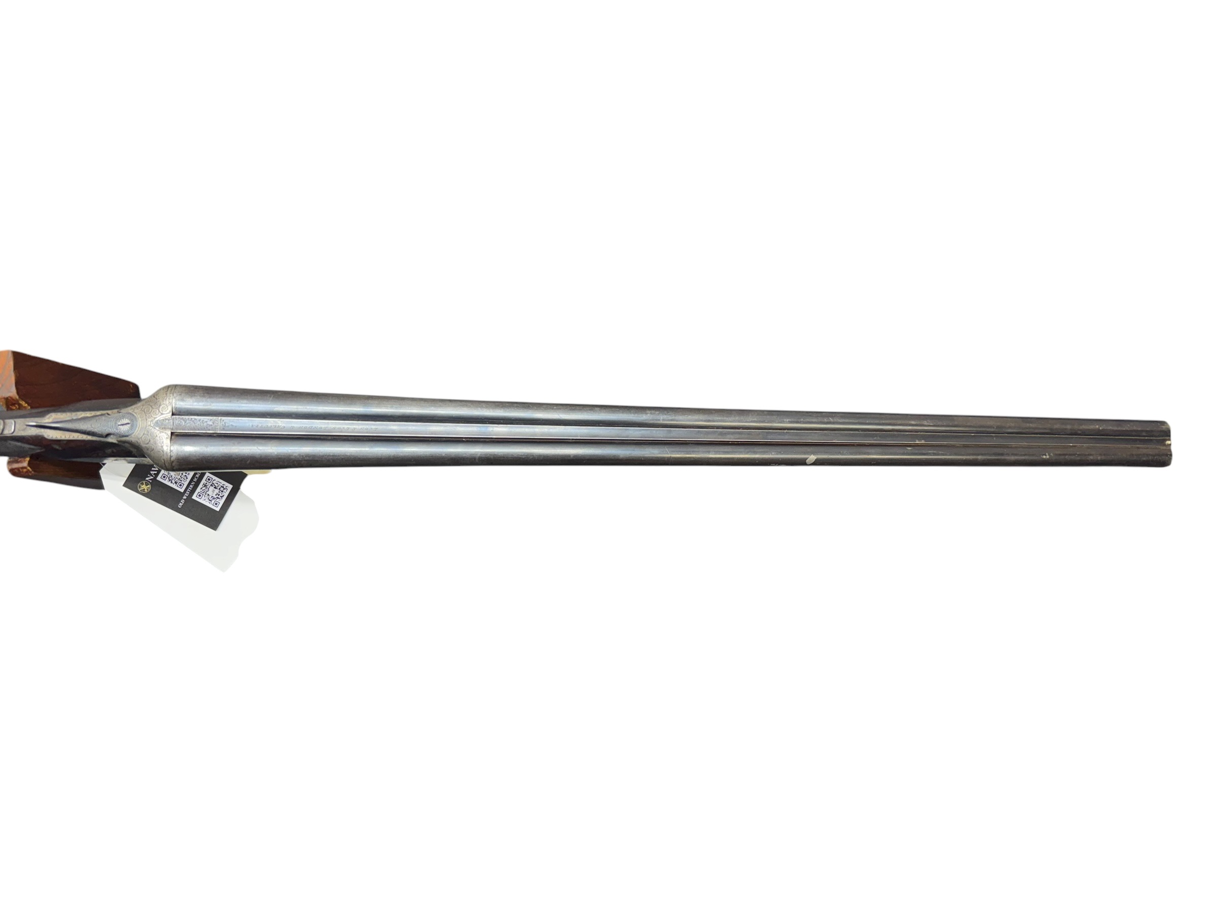 IMG_5384-Photoroom - OWS-Ammo Double-barreled shotgun shown horizontally with engraved metal receiver and wooden stock at left.