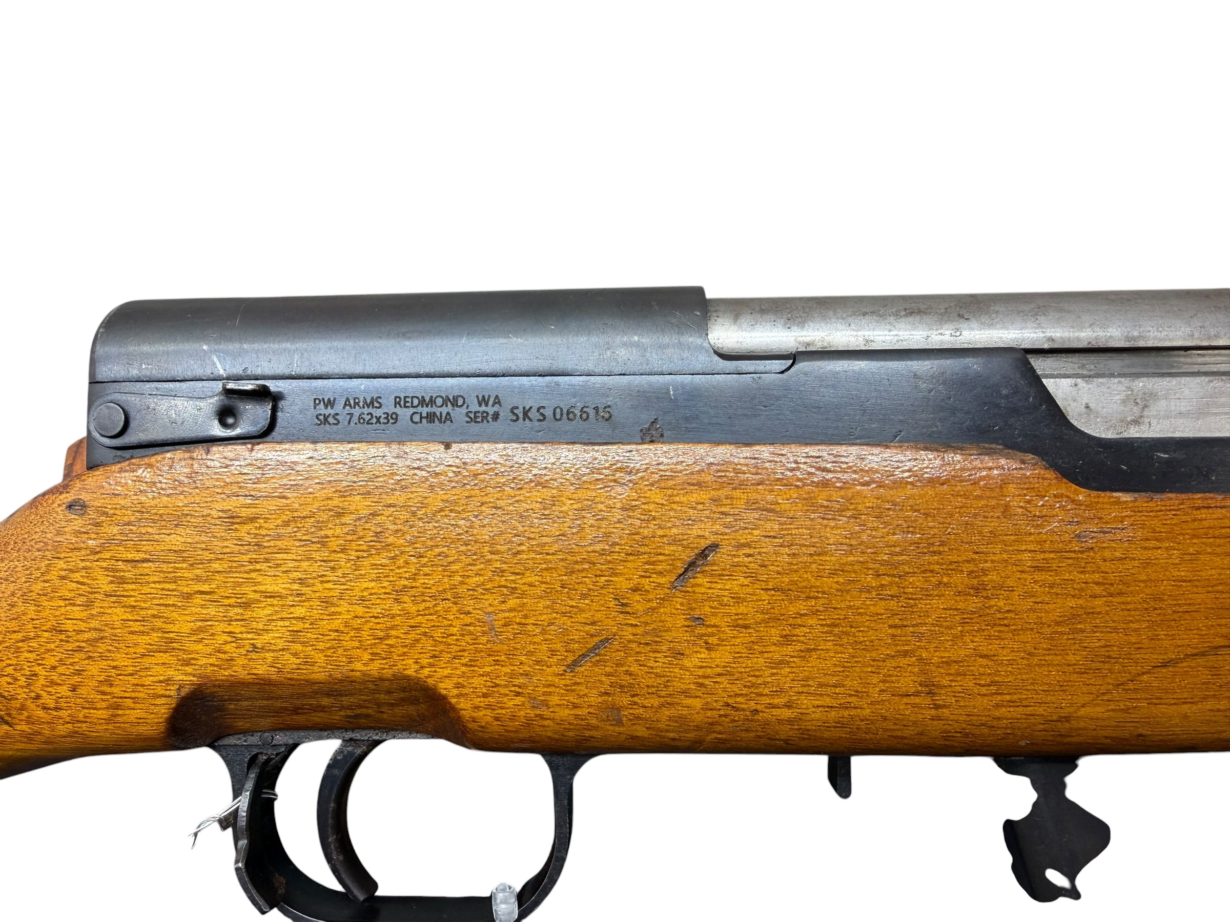 Close-up of a wooden-stocked SKS rifle with a metal receiver and stamped markings along the side.