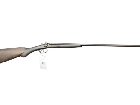 Side view of an antique rifle with a wooden stock and long metal barrel, tag hanging from trigger guard.