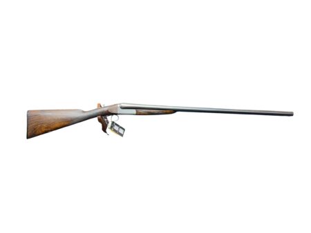 A single-barrel shotgun with a wooden stock and long metal barrel lying horizontally with a display tag near the trigger guard.
